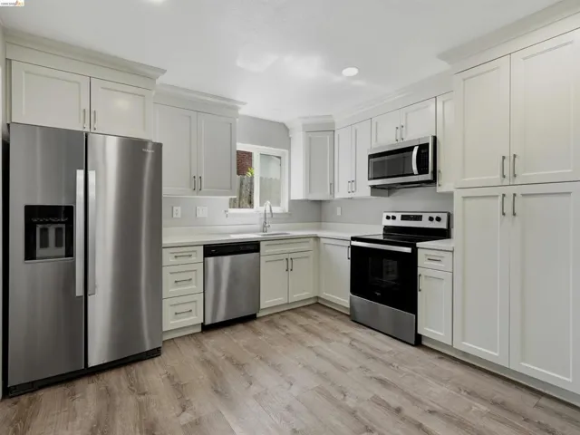 Kitchen featuring wood-finish flooring, white cabinetry, stainless steel appliances, white countertops, and recessed lighting