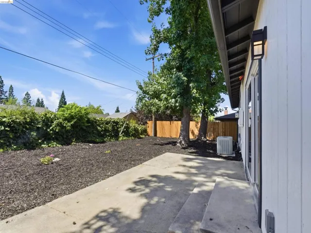 Concrete patio featuring two steps and an exterior light fixture