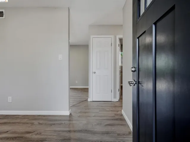 Black paneled entry door with glass inserts, brushed nickel hardware, and wood-finish flooring