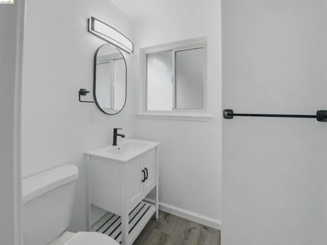 Bathroom featuring a white vanity with integrated sink, matte black faucet, and oval mirror