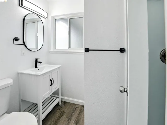Contemporary bathroom featuring a white vanity with integrated sink, matte black faucet, and oval mirror