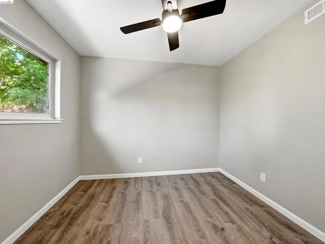 Room featuring wood-finish flooring, light grey walls, and a white ceiling with a contemporary ceiling fan light fixture