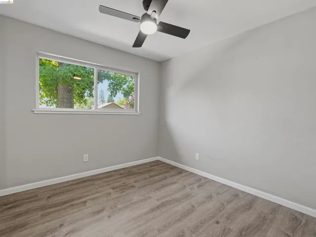 Room with light gray walls, wood-finish flooring, and a modern ceiling fan