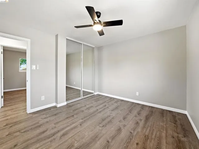 Spacious room featuring wood-finish flooring, light gray wall paint, and white baseboards