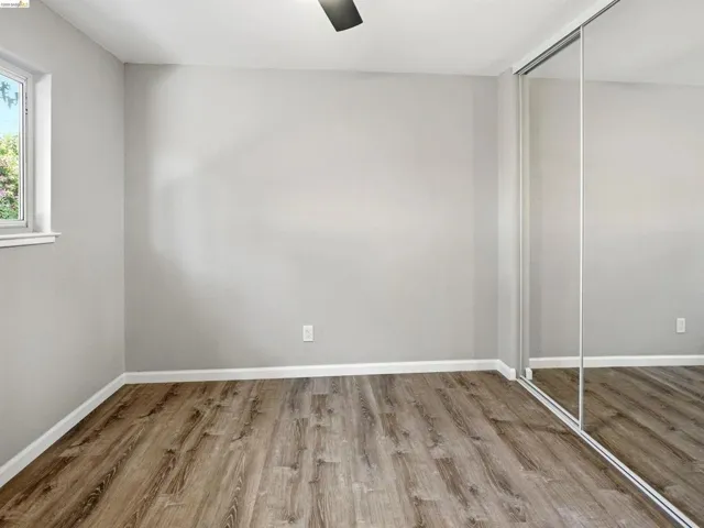 Spacious room featuring wood-finish flooring, light grey walls, and white baseboards
