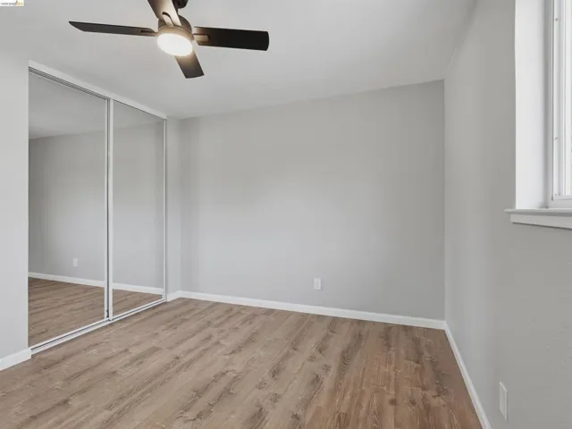 Room featuring wood-finish flooring, light grey walls, and white trim