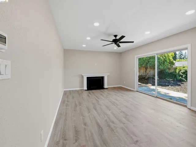 Spacious living area featuring wood-finish flooring, a fireplace with a white mantel, recessed lighting, and a ceiling fan
