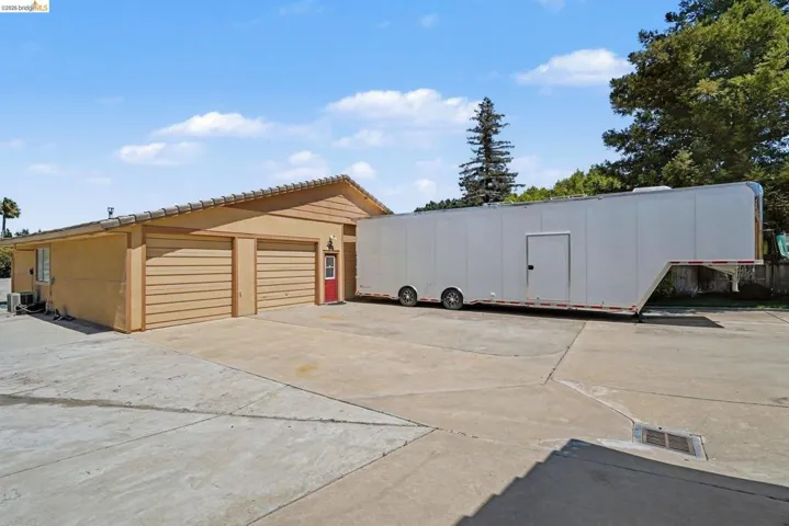 Two-car garage with horizontal panel doors, a red side entry door, and a concrete tile roof