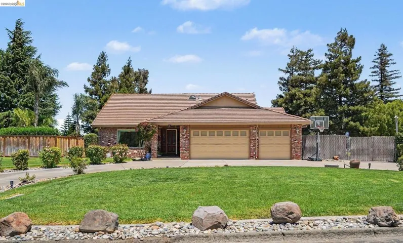 Single-story residence featuring a brick facade, a tiled roof, and a two-car garage