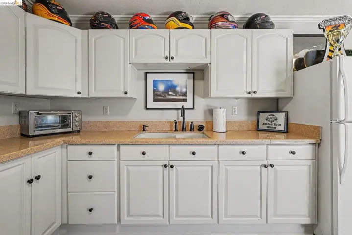 White shaker-style cabinetry with black hardware, complementing a light-toned countertop