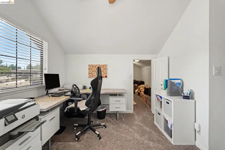 Carpeted room featuring a window with blinds, sloped ceilings, and neutral white walls