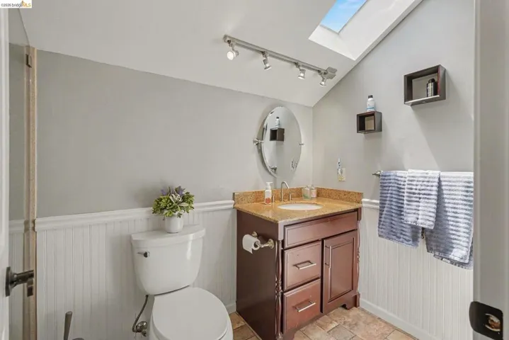 Bathroom featuring a skylight, track lighting, and wainscoting