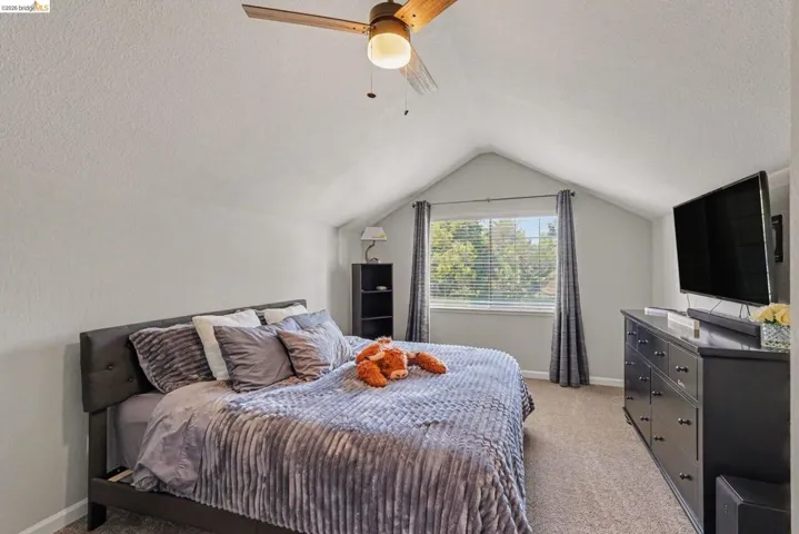 Bedroom featuring a vaulted ceiling and a wood-finish ceiling fan with integrated lighting