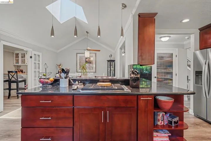 Kitchen featuring a central island with a built-in cooktop and dark countertop
