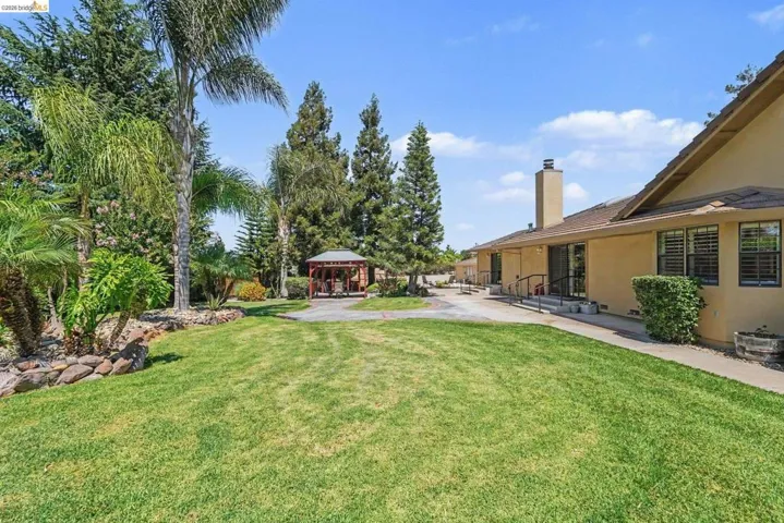 Expansive rear yard featuring a vast lawn area, mature trees, and a dedicated gazebo structure