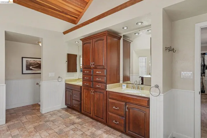 Bathroom featuring a dual vanity with wood cabinetry, light-toned countertops, and integrated sinks