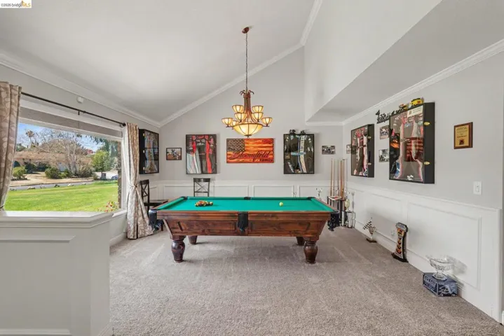 Spacious room featuring vaulted ceilings, wainscoting, and carpeted flooring