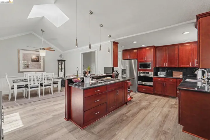 Kitchen featuring wood-finish flooring, dark wood cabinetry, and stainless steel appliances