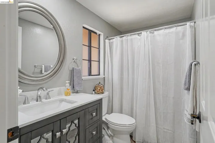 Bathroom featuring a dark gray vanity with mirrored accents, a white countertop, and an undermount sink