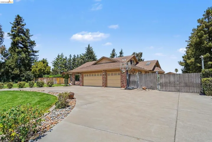 Spacious concrete driveway featuring a two-car garage with brick accents and wood-finish garage doors