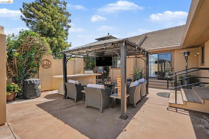 Outdoor entertaining area featuring a metal gazebo, built-in outdoor bar, paved patio, and a multi-level wood deck with handrails