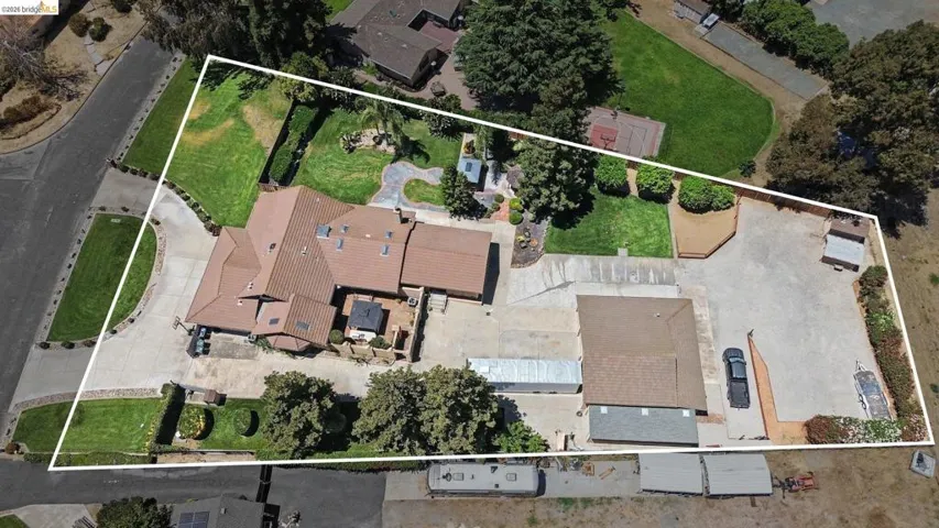 Expansive property featuring a multi-structure layout, substantial paved areas, and diverse landscaping