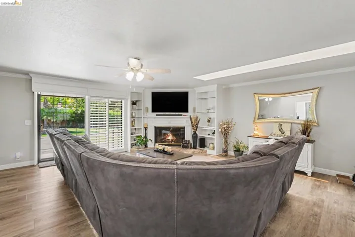 Living space featuring wood-finish flooring and a corner fireplace with a white mantel and built-in shelving