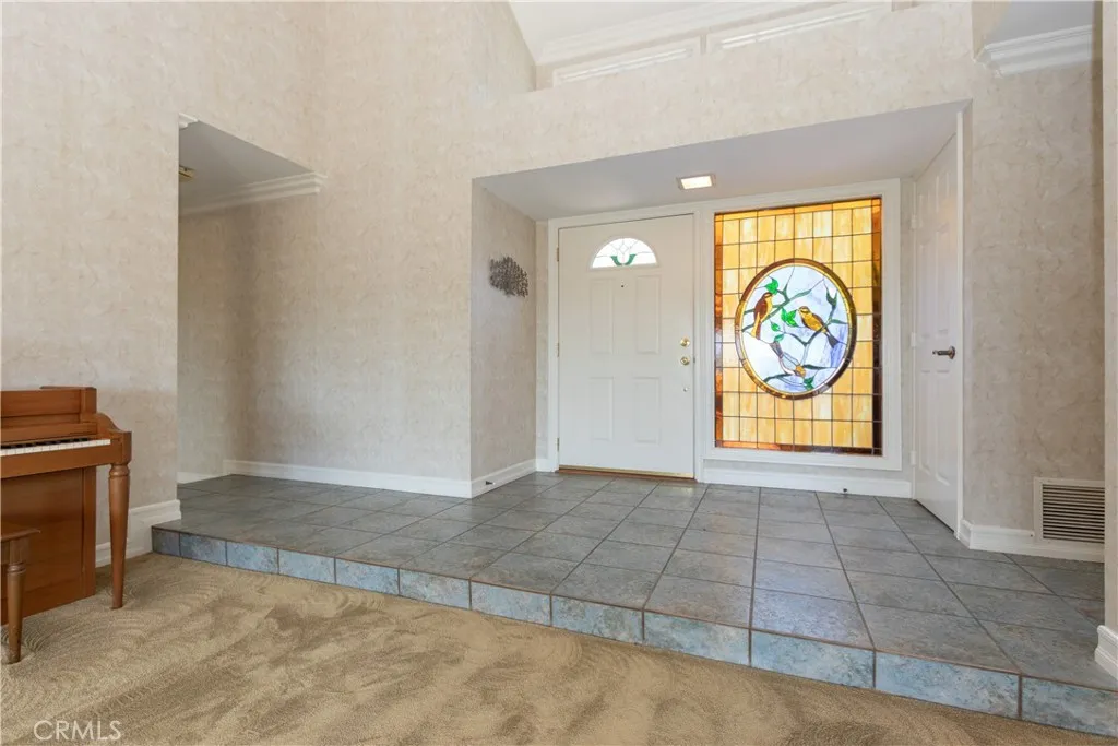 Enter to a tiled foyer with stained glass window.