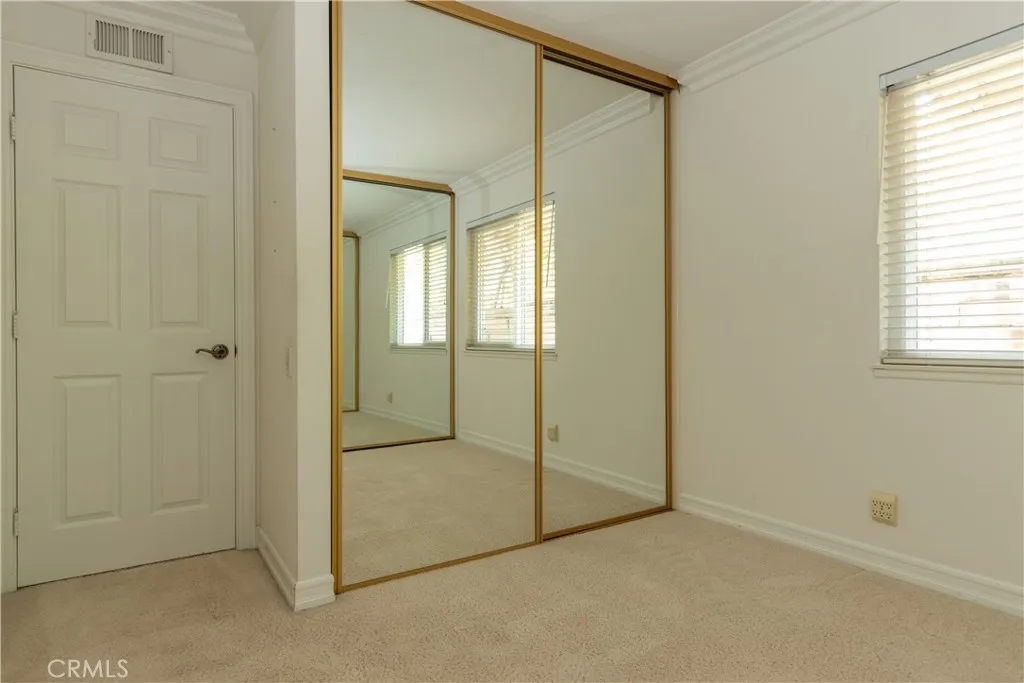 Secondary bedroom with dual mirrored wardrobes.