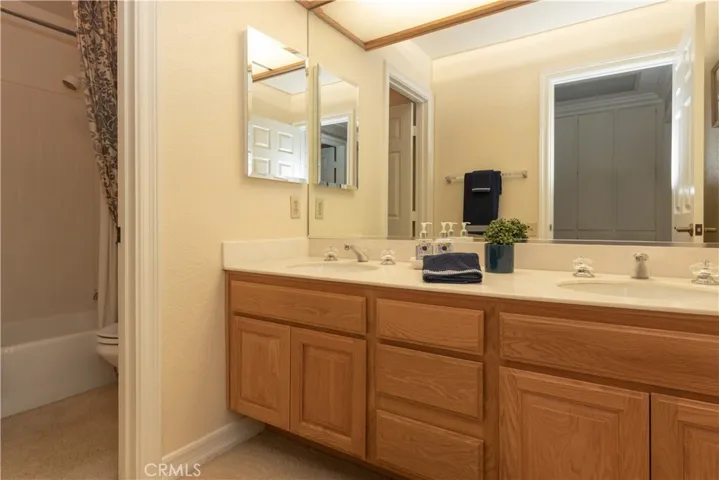 Full hall bath has dual vanity and separate tub and toilet room.