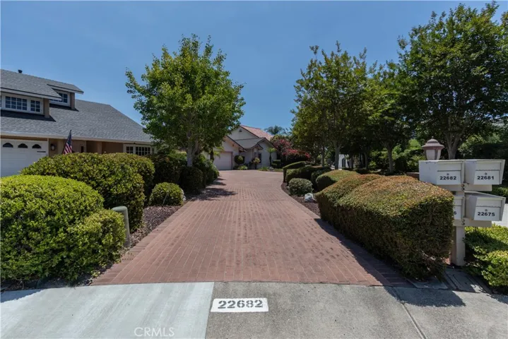 Flag lot with paver driveway lined by well manicured shrubs.