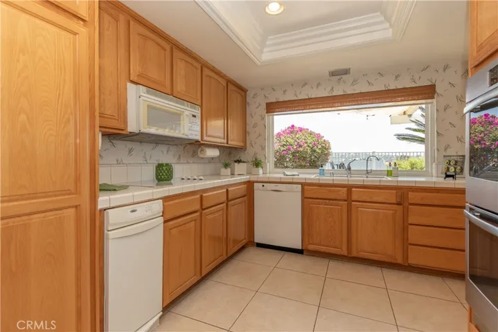 Cheerful kitchen with tile floor and tray ceiling.