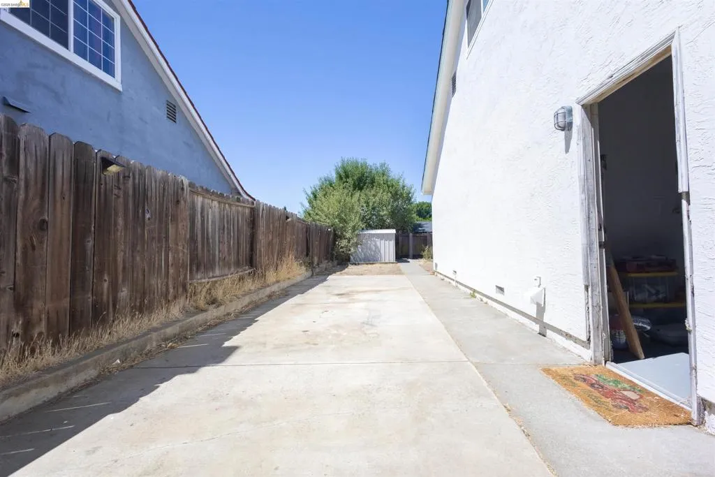 Concrete side yard with a full-height wooden fence