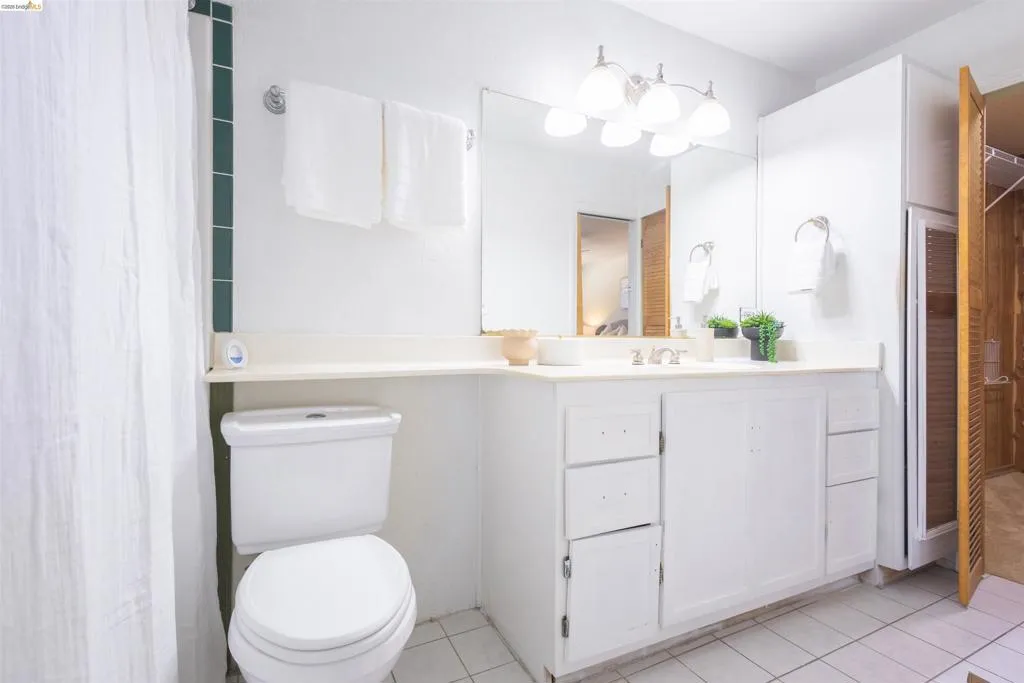 Bathroom featuring a white vanity with integrated sink, a large wall-mounted mirror, and overhead vanity lighting