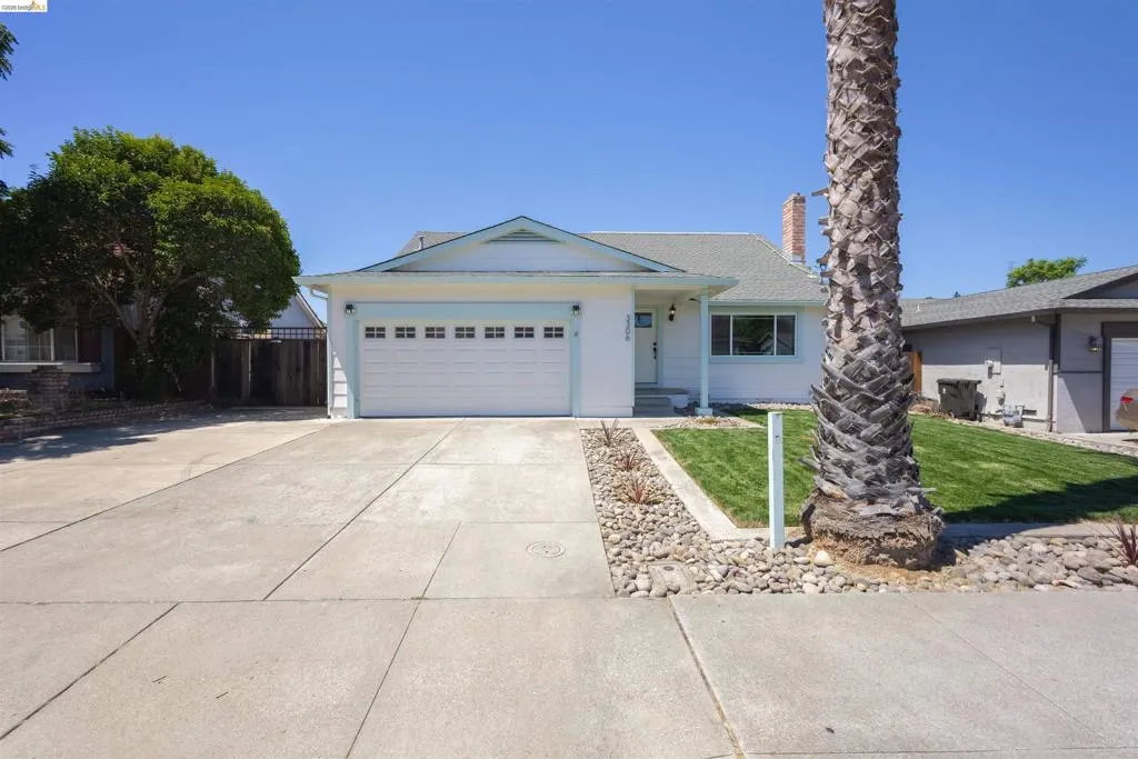 Single-story residence featuring a two-car garage, concrete driveway, and a front yard with mature landscaping