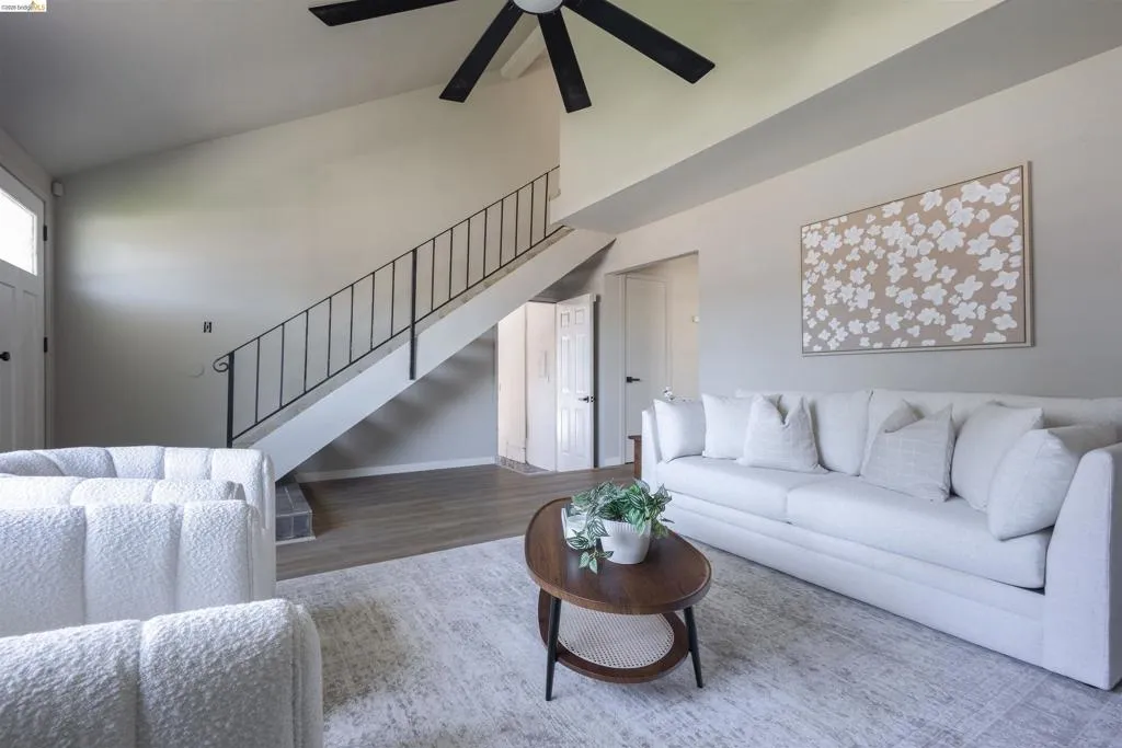 Living area featuring vaulted ceilings, a contemporary ceiling fan, and wood-finish flooring