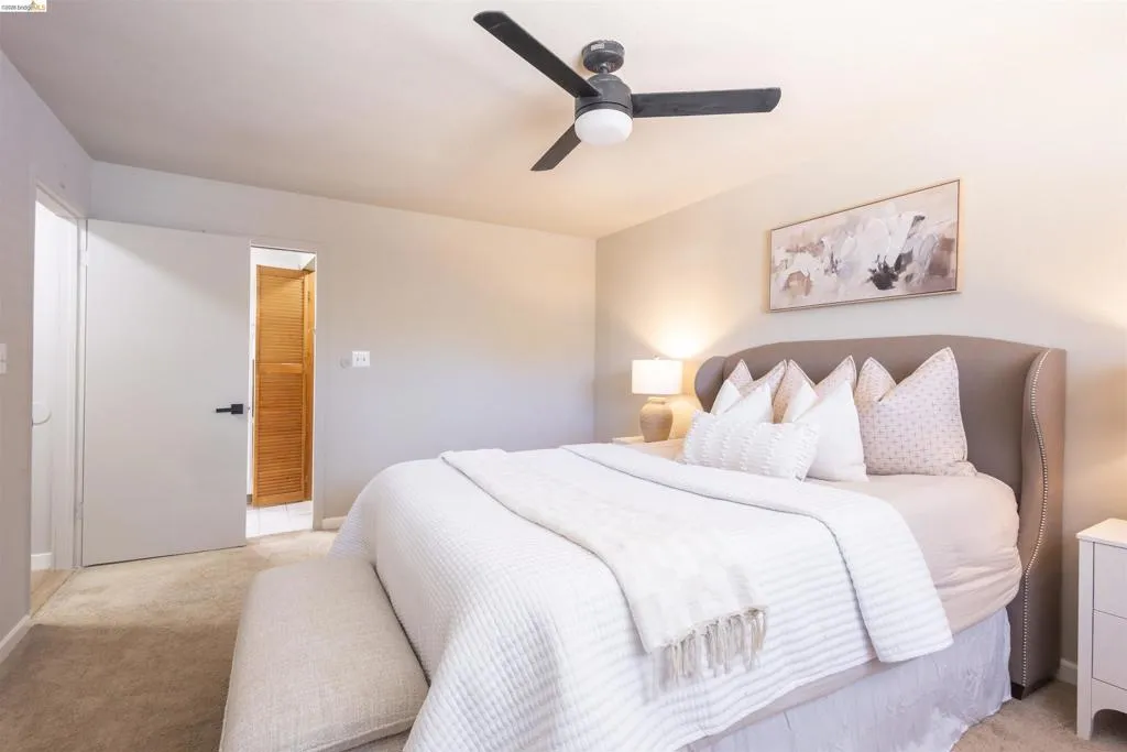 Bedroom featuring a flush-mount ceiling fan with black blades, neutral wall paint, and carpeted flooring