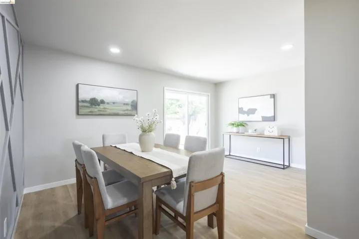 Dining area featuring light wood-finish flooring, recessed lighting, and a decorative accent wall