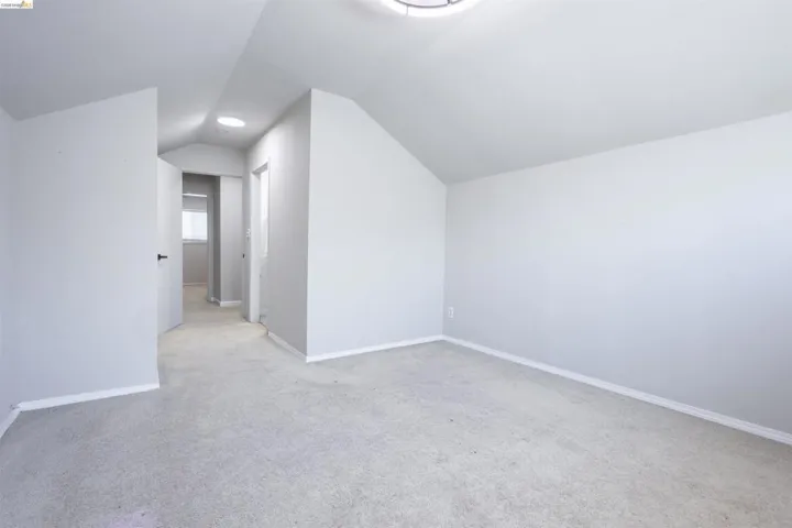 Carpeted room with vaulted ceilings and light gray wall color