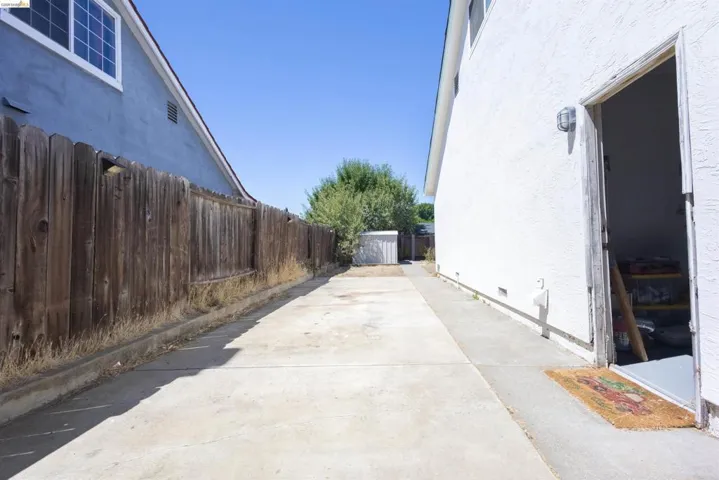 Concrete side yard with a full-height wooden fence