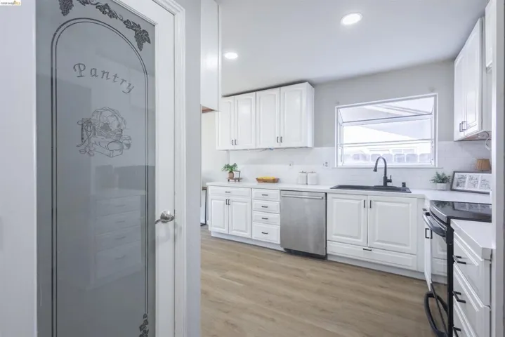 Kitchen featuring white cabinetry, light countertops, wood-finish flooring, recessed lighting, and a frosted glass pantry door