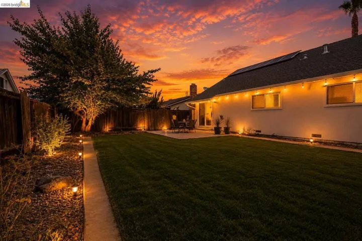 Expansive backyard featuring a lush lawn, concrete patio, and perimeter fencing