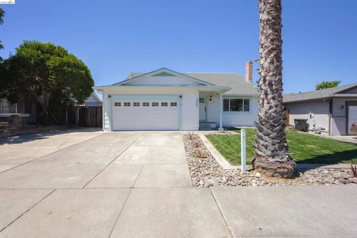 Single-story residence featuring a two-car garage, concrete driveway, and a front yard with mature landscaping