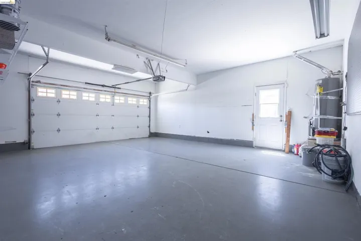 Two-car garage featuring a painted concrete floor, white walls, and overhead fluorescent lighting