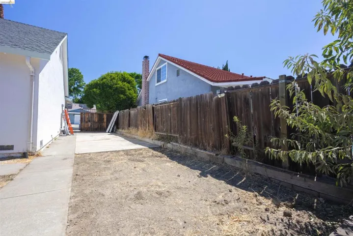 Rear yard area featuring a concrete pad and a wood fence