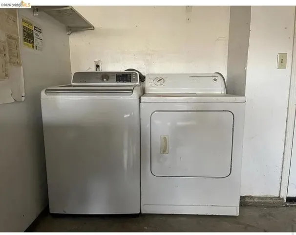 Dedicated laundry space featuring a white top-load washing machine and a white front-load dryer