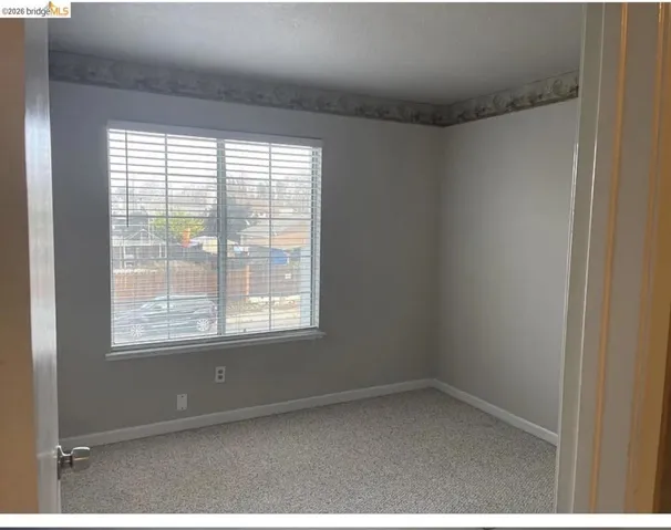 Room featuring a neutral color palette, window with horizontal blinds, light-toned carpeting, and baseboard trim