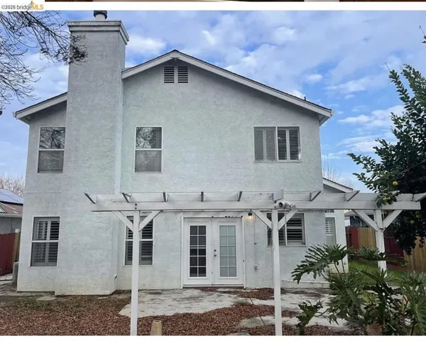 Rear exterior featuring a pergola, stucco finish, and French doors