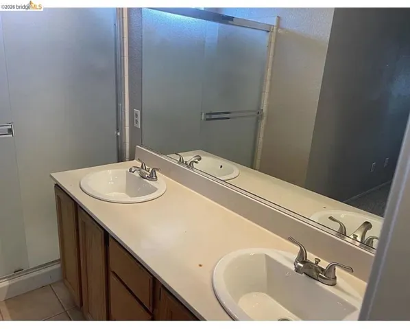 Dual vanity featuring two undermount sinks, brushed nickel faucets, and a full-width mirror