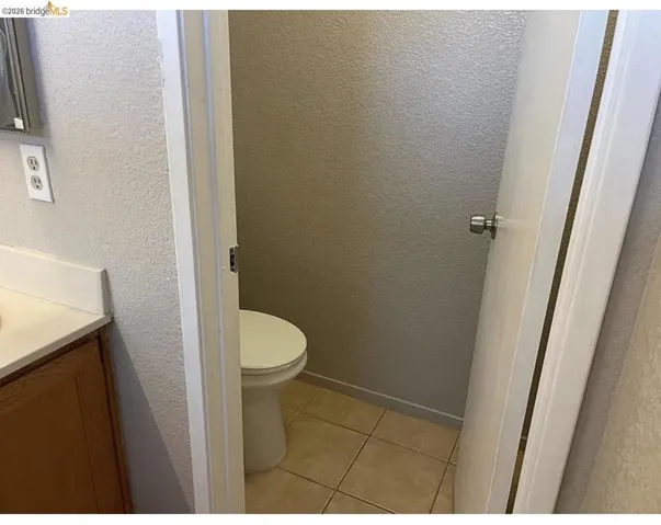 Powder room featuring a standard white toilet, ceramic tile flooring, and light neutral wall finishes